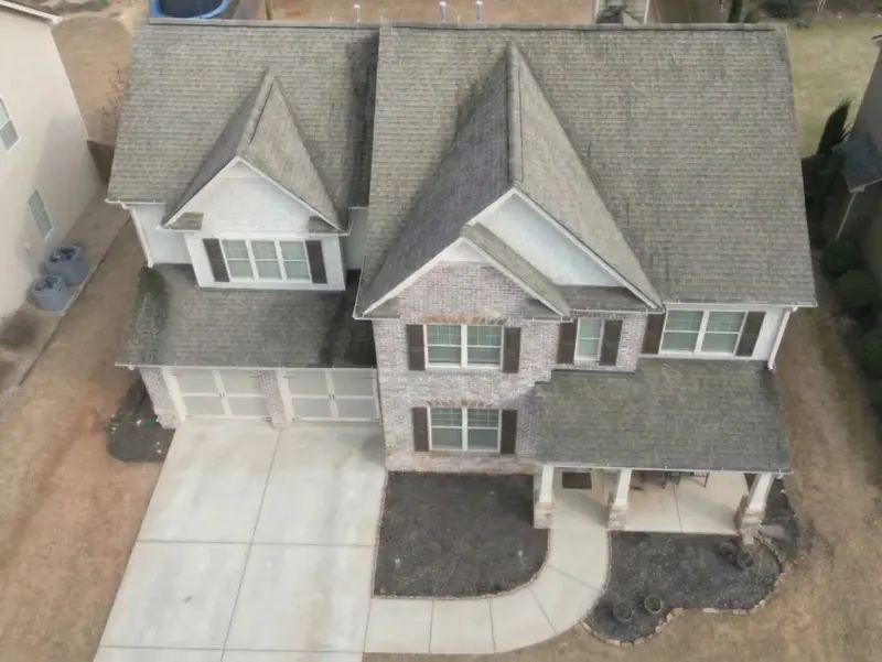Two-story brick home with a worn, stained roof before replacement