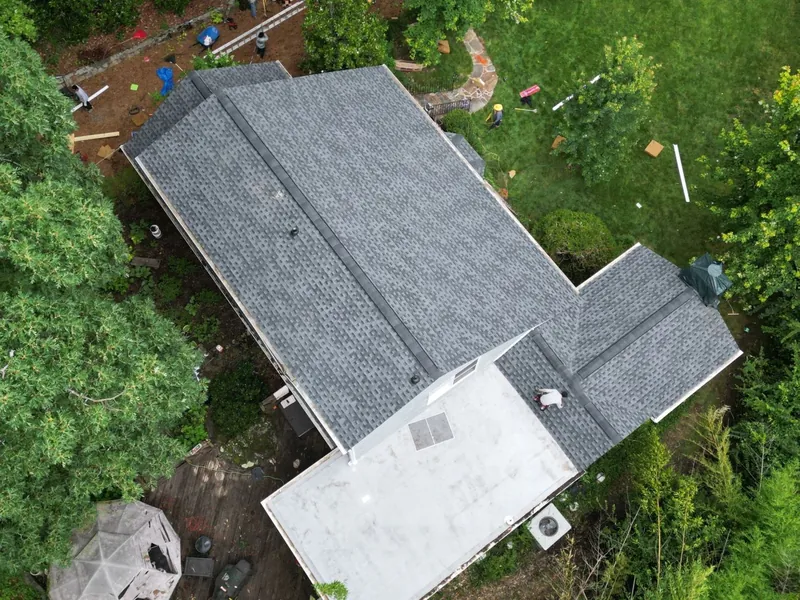 Overhead drone view of a Canton, GA home with a new architectural shingle roof and a low-slope section in back, crew working in the yard