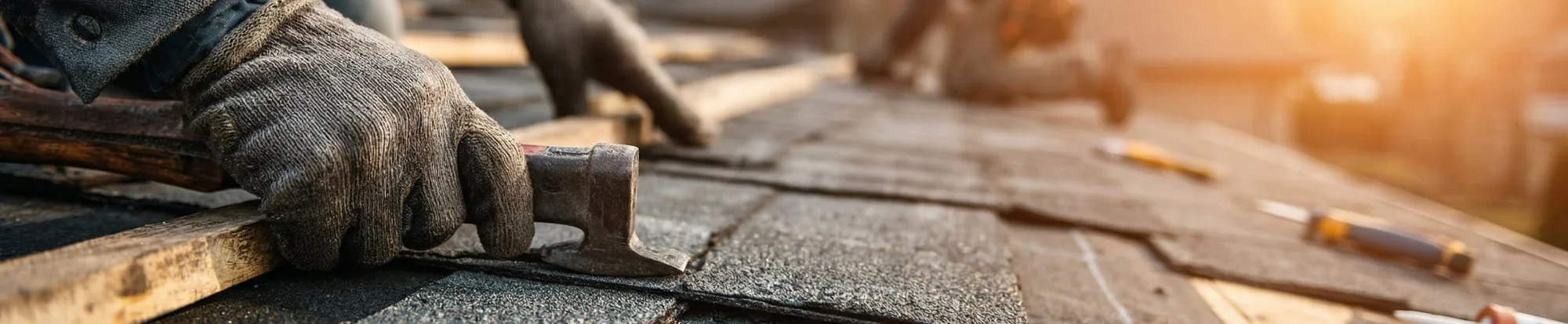 Roofer nailing shingles at golden hour