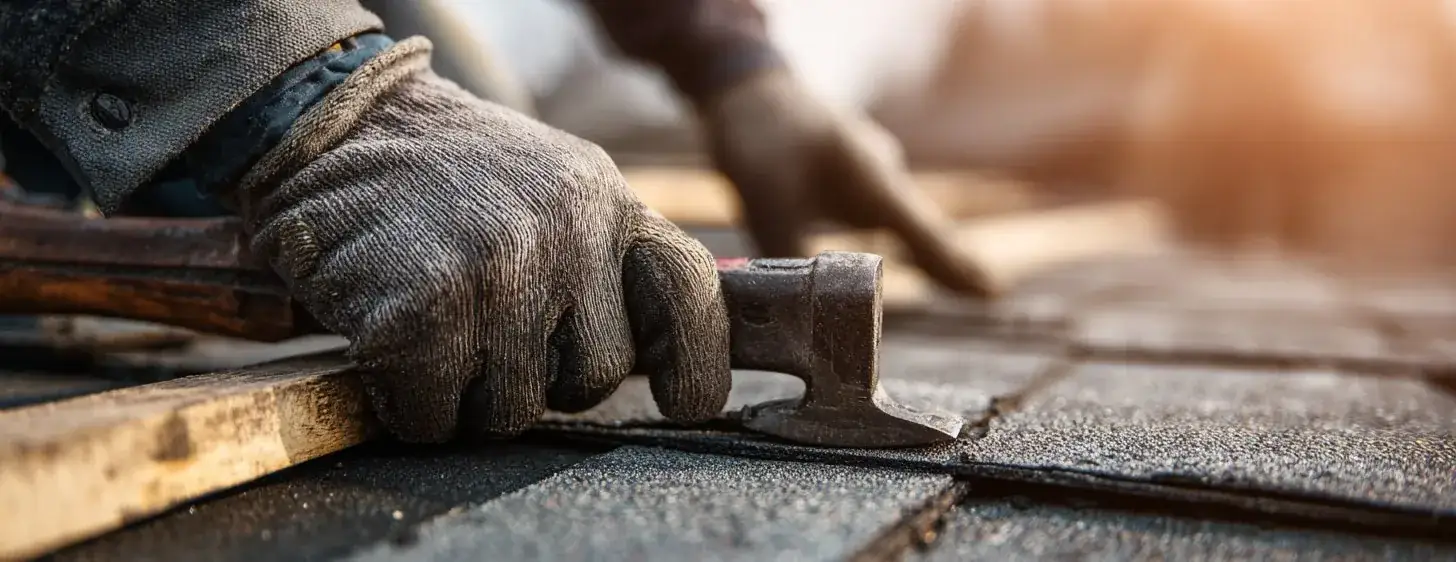 North Metro roofer working with hatchet on shingle roof