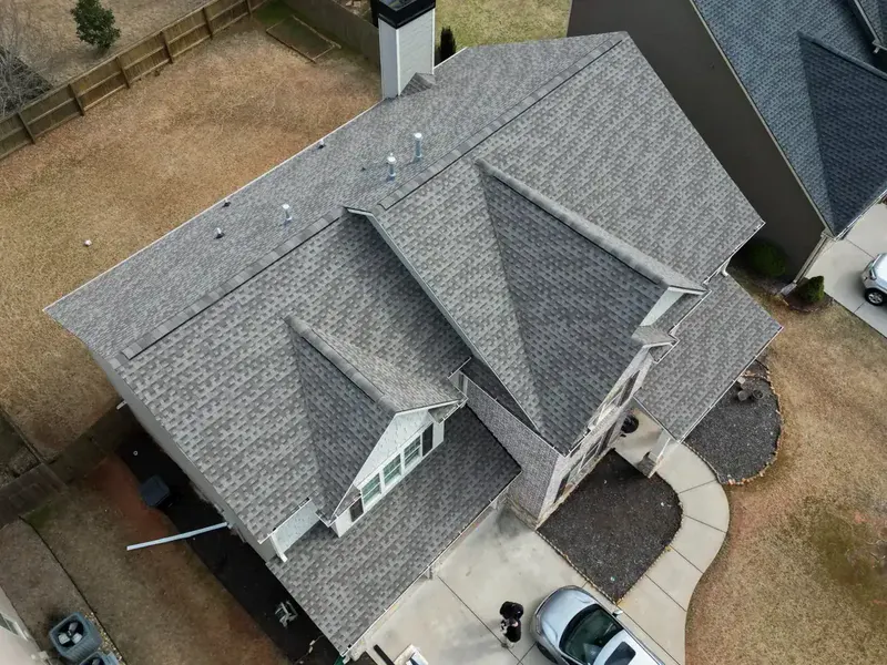 Aerial view of a two-story home with a new gray architectural shingle roof, dormers and valleys