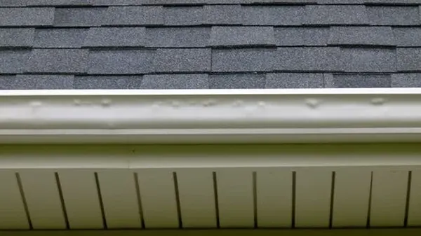 Hail dents visible on white aluminum gutter